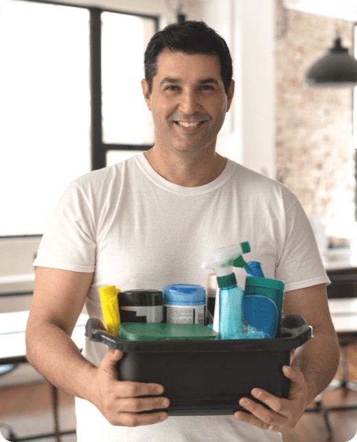 a cheerful man holding a basket of cleaning essentials