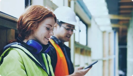 A young man wearing headphones and smiling at the desktop.