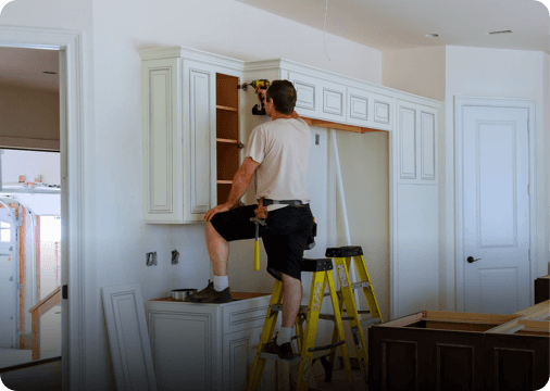 A man standing on top of a tiny ladder remodeling his home