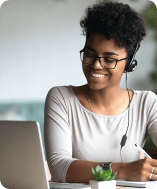 A smiling woman looking at her laptop wearing headphones