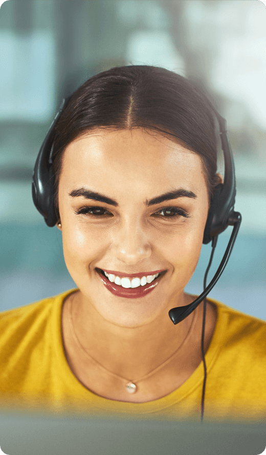 A smiling woman looking at her laptop wearing headphones