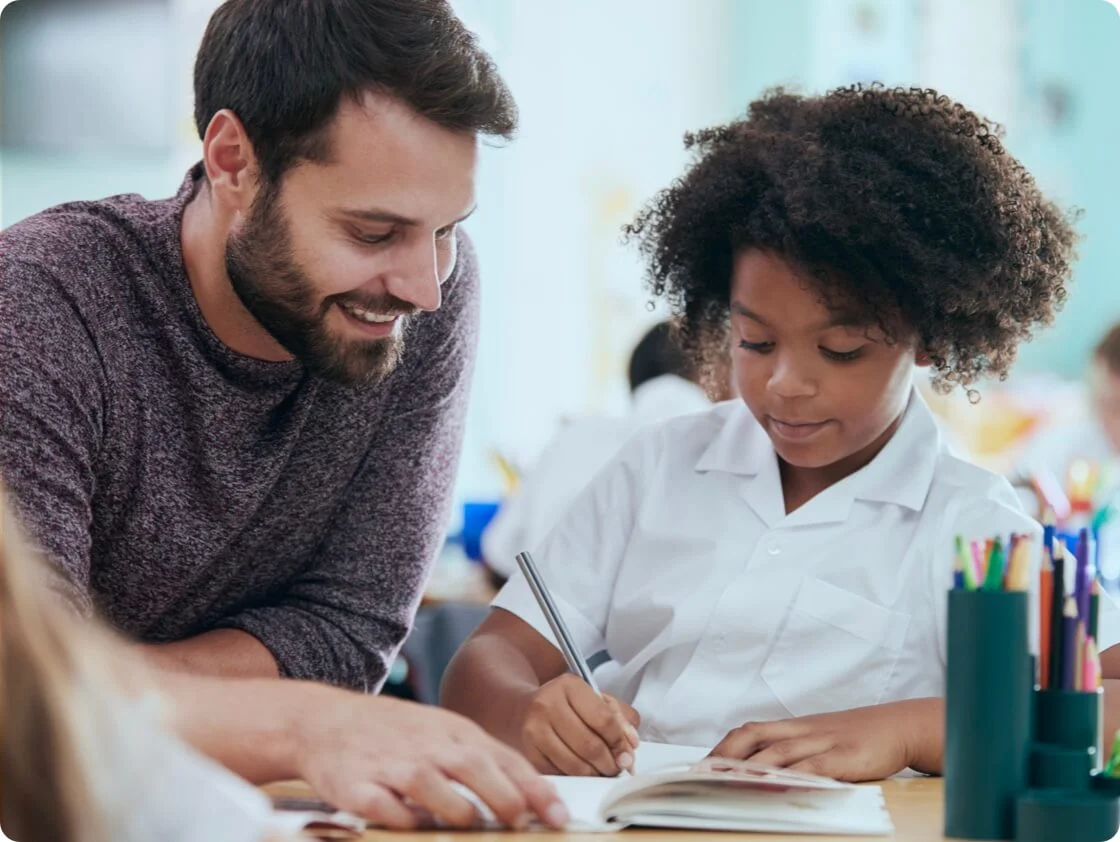 a smiling young man teaching a child