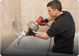 man using tools to clean bath tub